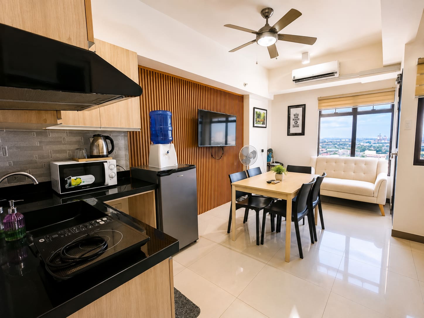 Kitchen with induction cooktop, microwave and refrigerator opening onto the dining table, loveseat and ceiling fan