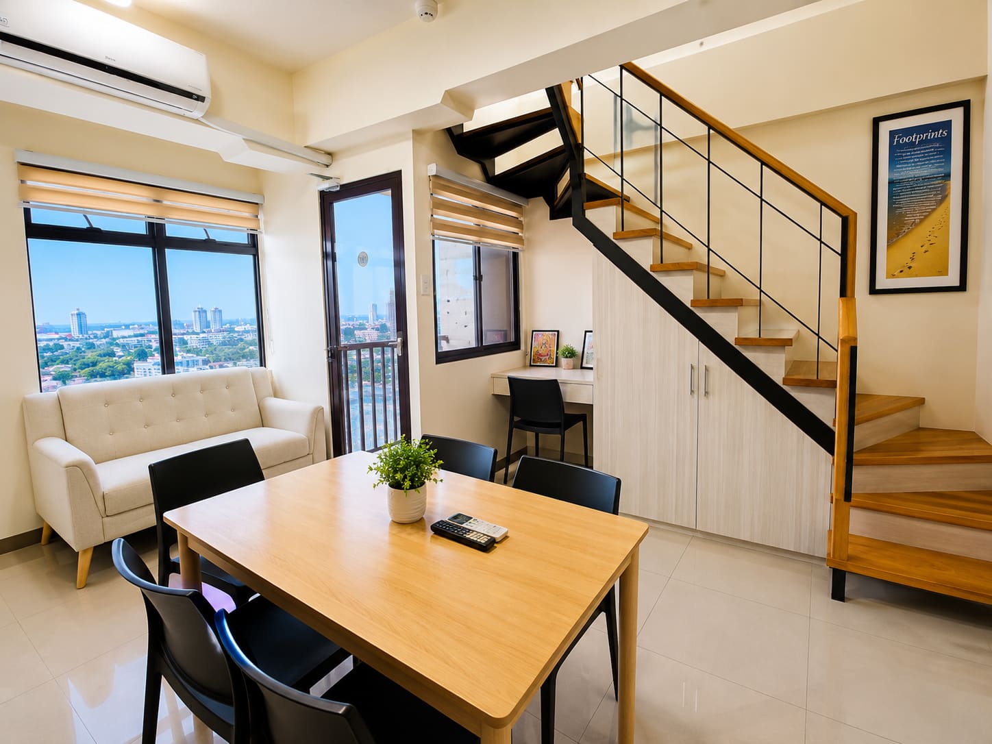 Living and dining area of Loft 1512 with a wooden staircase, loveseat and big windows over Cebu City